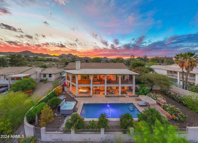 back house at dusk featuring a gazebo, a swimming pool with hot tub, and a patio area