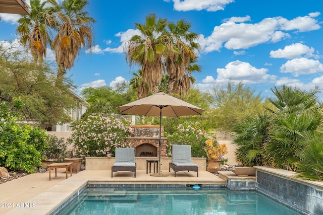 view of swimming pool featuring a patio and an outdoor stone fireplace