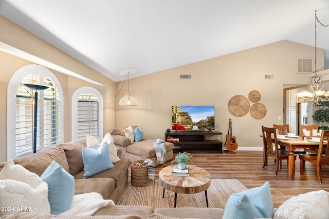 living room with a chandelier, light hardwood / wood-style flooring, and lofted ceiling