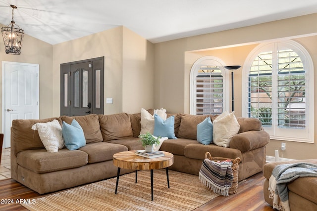 living room featuring an inviting chandelier, light hardwood / wood-style flooring, and lofted ceiling