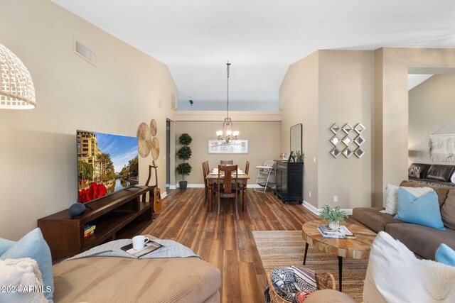 living room featuring a notable chandelier, dark wood-type flooring, and vaulted ceiling