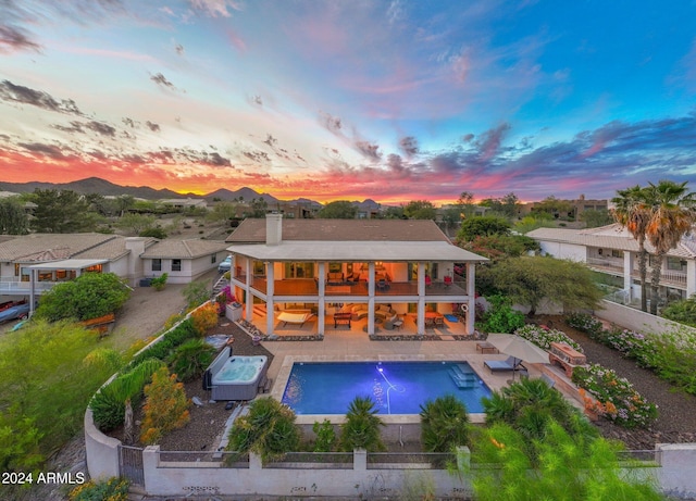 15857 E Ponderosa Dr, Fountain Hills, AZ 85268 - back of property at dusk featuring a balcony, a fenced backyard, an outdoor hot tub, a chimney, and outdoor lounge area