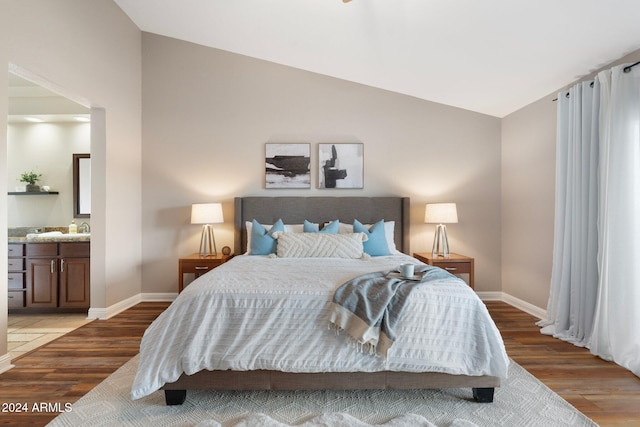 bedroom with hardwood / wood-style floors, ensuite bath, and vaulted ceiling