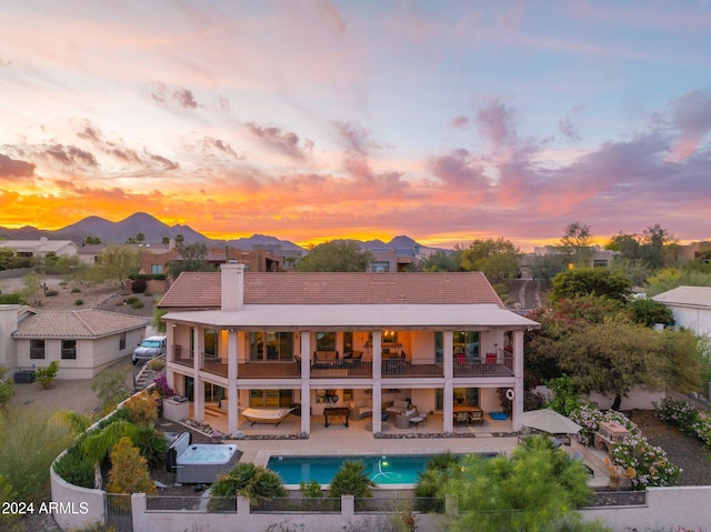 back house at dusk with a balcony and a patio area