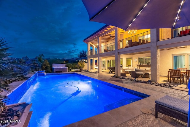 view of pool featuring a jacuzzi, pool water feature, a patio, and an outdoor living space