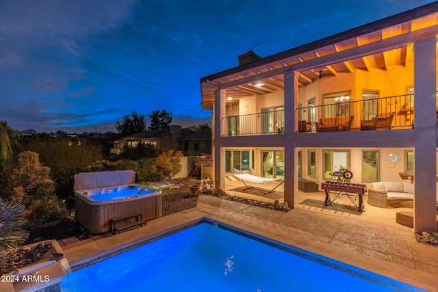 pool at dusk featuring outdoor lounge area, a patio, and a hot tub