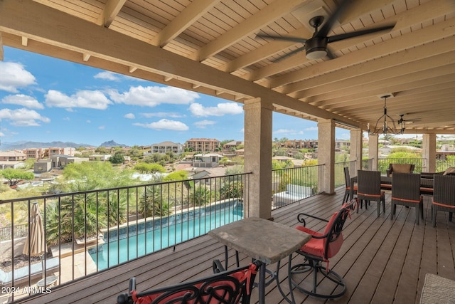 deck featuring a fenced in pool, a mountain view, and ceiling fan