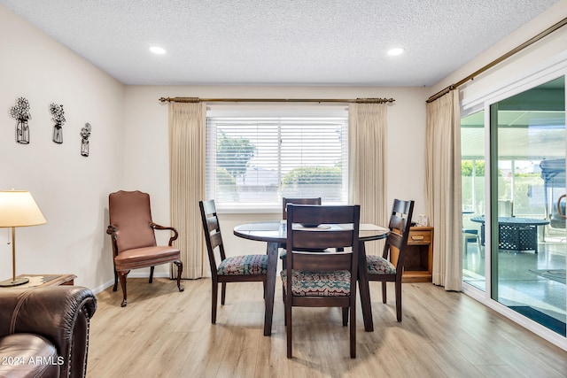 dining space featuring light wood-type flooring and a textured ceiling