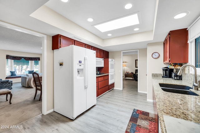 kitchen featuring light hardwood / wood-style floors, white appliances, sink, and a tray ceiling