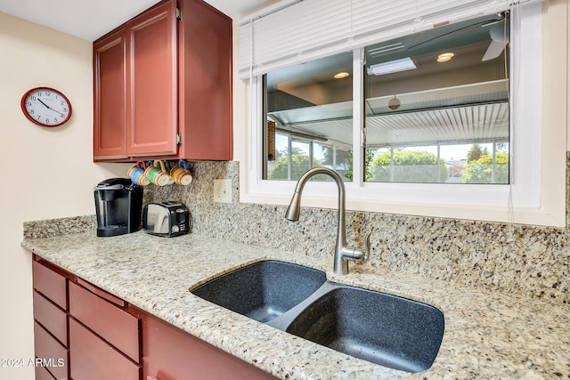 kitchen featuring decorative backsplash, light stone countertops, and sink