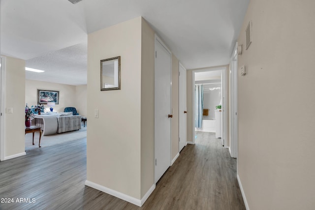 hall with wood-type flooring and a textured ceiling