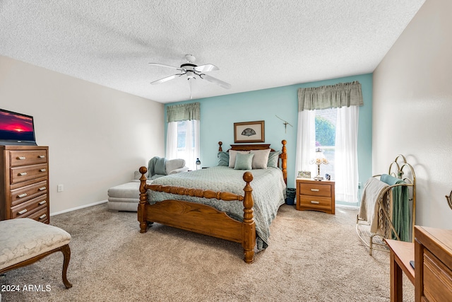 bedroom featuring ceiling fan, light colored carpet, and a textured ceiling