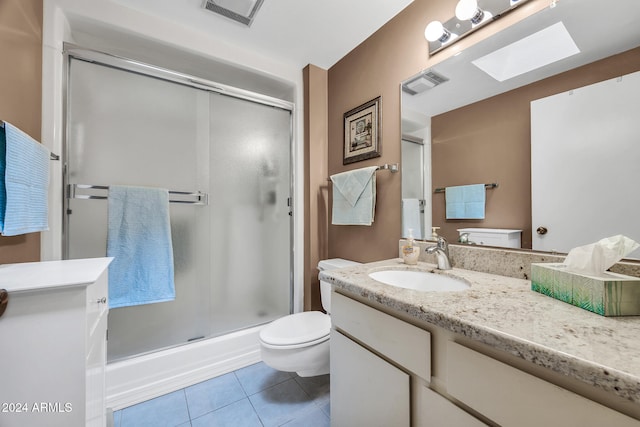 bathroom featuring a skylight, tile patterned flooring, an enclosed shower, toilet, and vanity