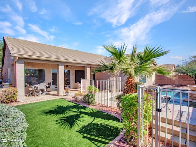 rear view of house with a fenced in pool, a patio area, and a lawn