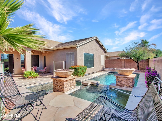 view of swimming pool with pool water feature and a patio