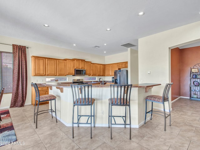 kitchen featuring a breakfast bar, a kitchen island with sink, stainless steel appliances, and sink