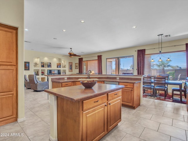 kitchen featuring sink, light tile patterned floors, pendant lighting, and an island with sink