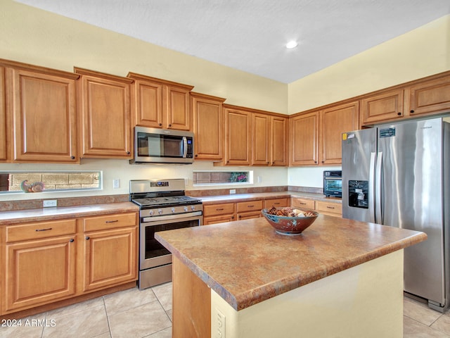 kitchen with appliances with stainless steel finishes, light tile patterned flooring, and a kitchen island