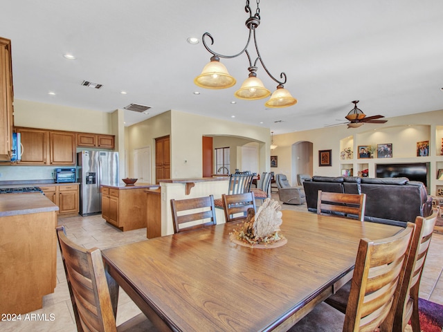 tiled dining area with ceiling fan with notable chandelier