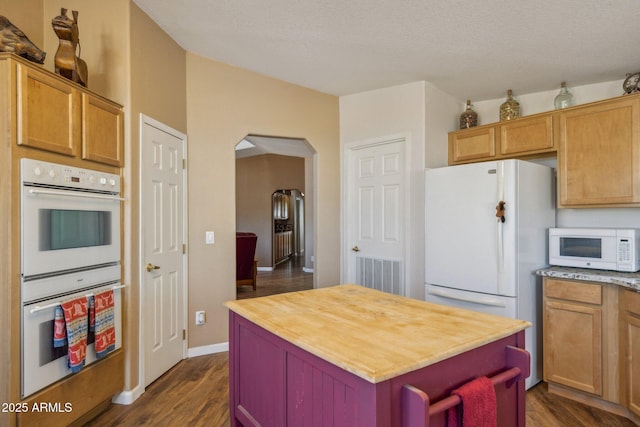 kitchen with arched walkways, white appliances, dark wood-type flooring, and visible vents