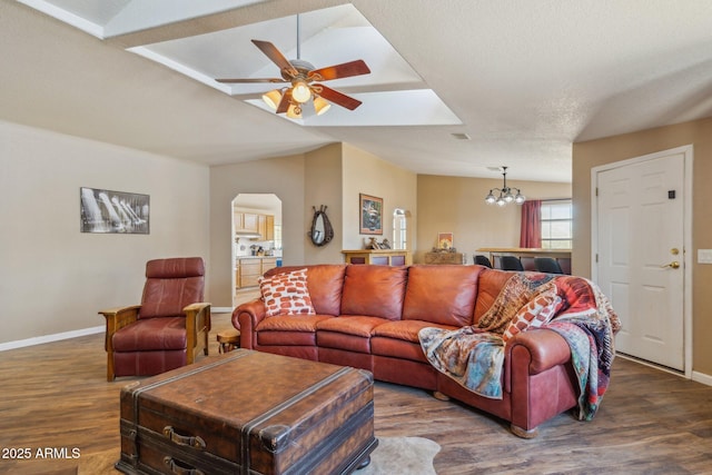 living room with vaulted ceiling, ceiling fan with notable chandelier, wood finished floors, and baseboards