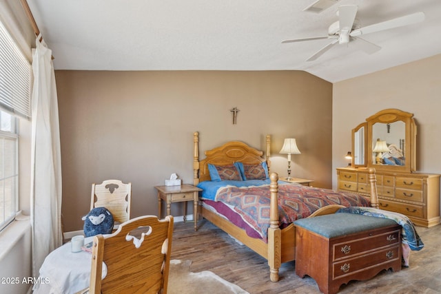 bedroom with baseboards, visible vents, a ceiling fan, lofted ceiling, and wood finished floors