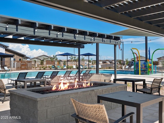 community pool with an outdoor fire pit, a water play area, fence, and a pergola