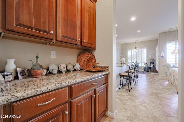 kitchen with decorative light fixtures, light stone countertops, and light tile patterned floors