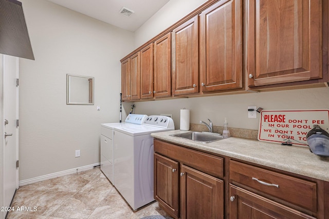 clothes washing area with cabinets, independent washer and dryer, and sink