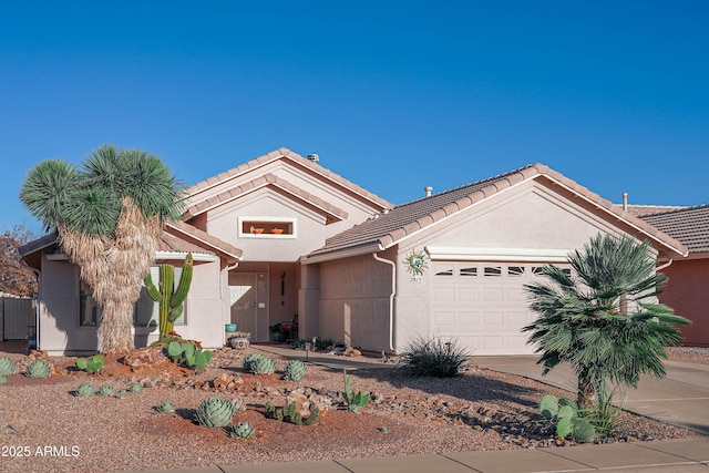 view of front of property featuring an attached garage, a tile roof, concrete driveway, and stucco siding