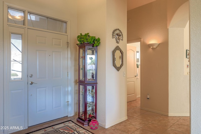 entrance foyer featuring light tile patterned floors, baseboards, and arched walkways