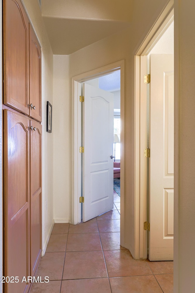 hall with light tile patterned flooring and baseboards