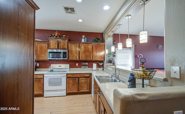 kitchen with brown cabinets, white electric range oven, a sink, stainless steel microwave, and visible vents