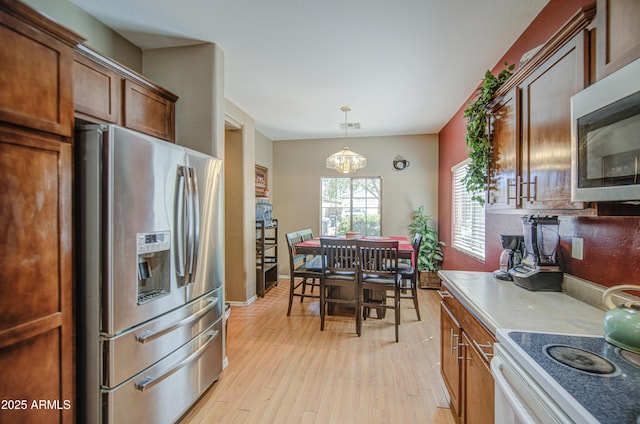 kitchen featuring appliances with stainless steel finishes, an inviting chandelier, light wood-style flooring, decorative light fixtures, and visible vents