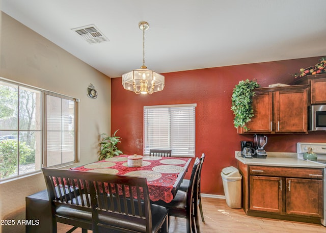 dining room with visible vents, light wood-type flooring, and an inviting chandelier