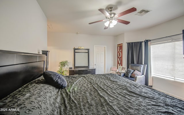 bedroom featuring ceiling fan, visible vents, and multiple windows