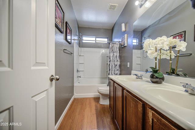 full bathroom featuring toilet, a textured wall, a sink, and wood finished floors