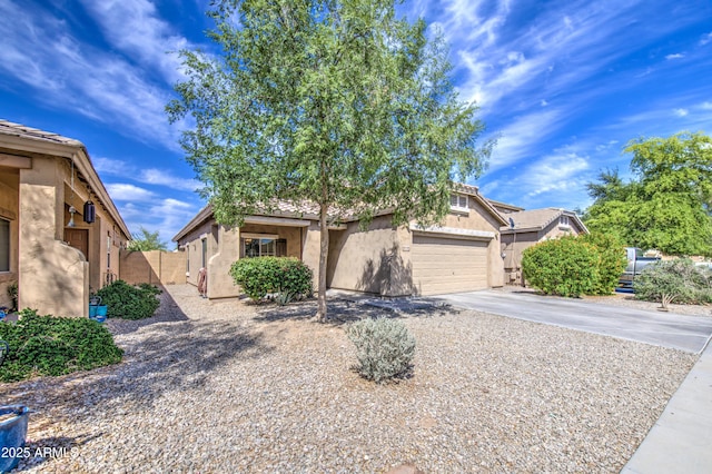 view of front of house with concrete driveway, stucco siding, fence, and a garage