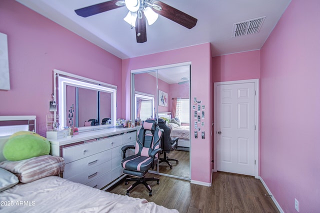 bedroom featuring a ceiling fan, visible vents, wood finished floors, baseboards, and a closet