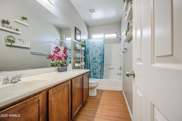 full bath with vanity, toilet, wood finished floors, shower / tub combo, and visible vents