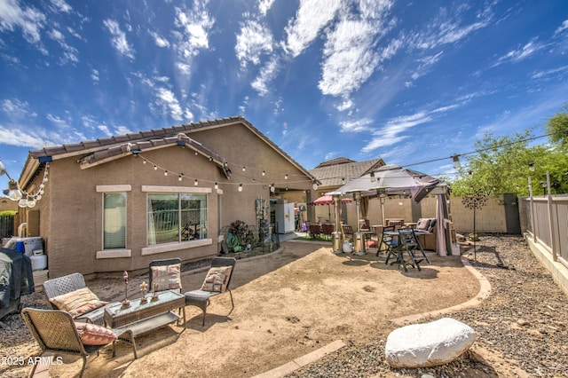 rear view of house featuring a gazebo, a fenced backyard, stucco siding, and a patio