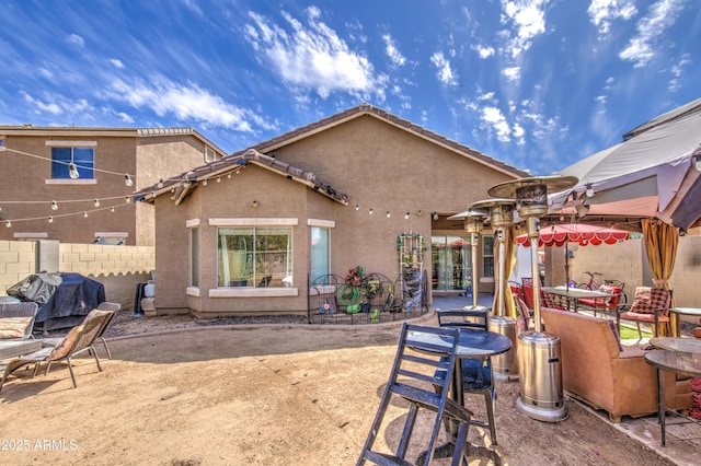rear view of property with fence, a patio, stucco siding, and outdoor dining space
