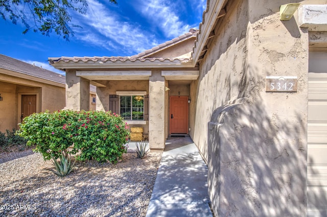 entrance to property featuring stucco siding and a tiled roof