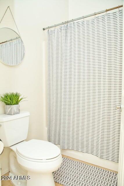 bathroom with a shower with shower curtain and toilet