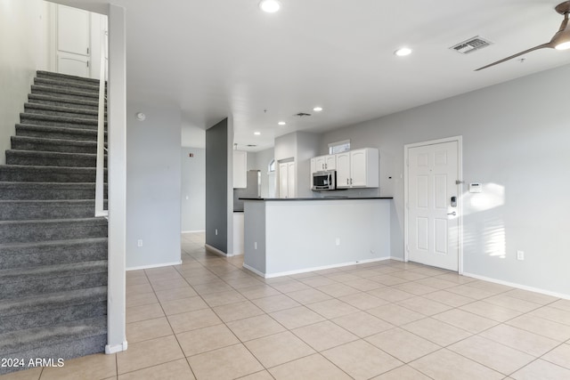 kitchen with white cabinets, kitchen peninsula, and light tile patterned floors