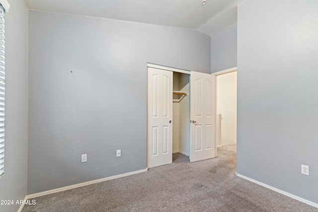 unfurnished bedroom with light colored carpet, vaulted ceiling, and a closet