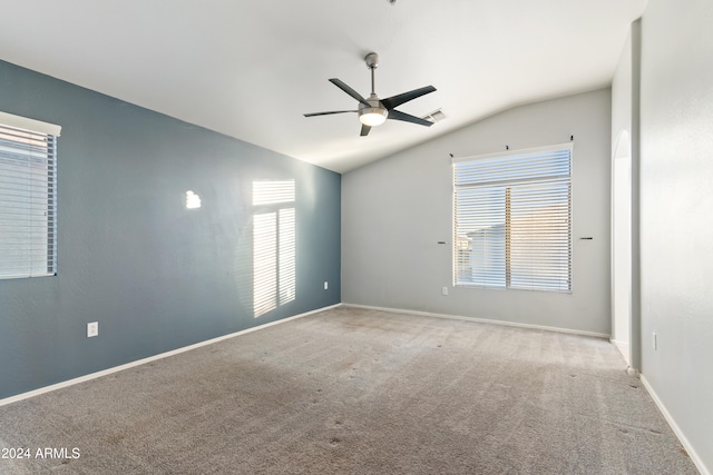 carpeted spare room featuring vaulted ceiling, a wealth of natural light, and ceiling fan