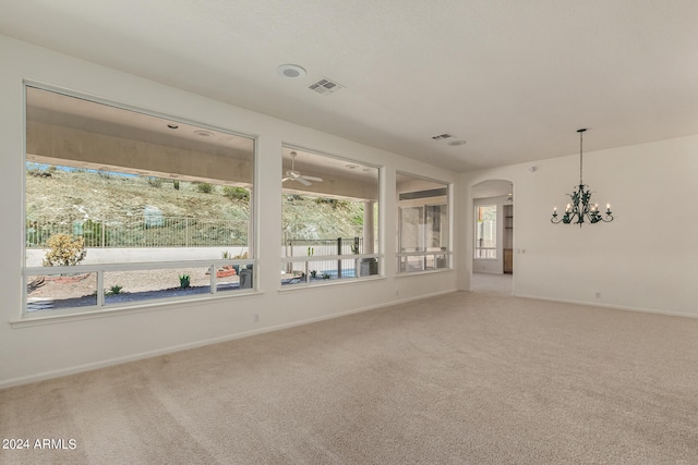 spare room featuring carpet floors and a chandelier