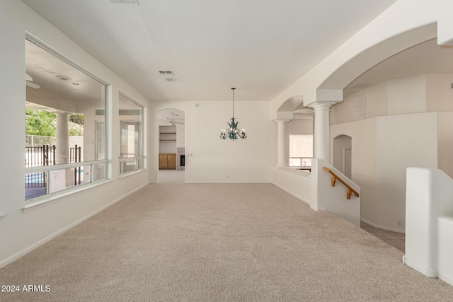 unfurnished room featuring carpet floors, arched walkways, a healthy amount of sunlight, and decorative columns