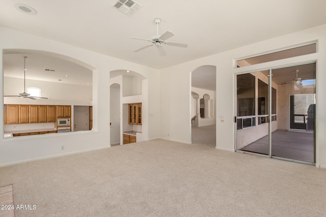 unfurnished living room featuring carpet floors, visible vents, ceiling fan, and baseboards